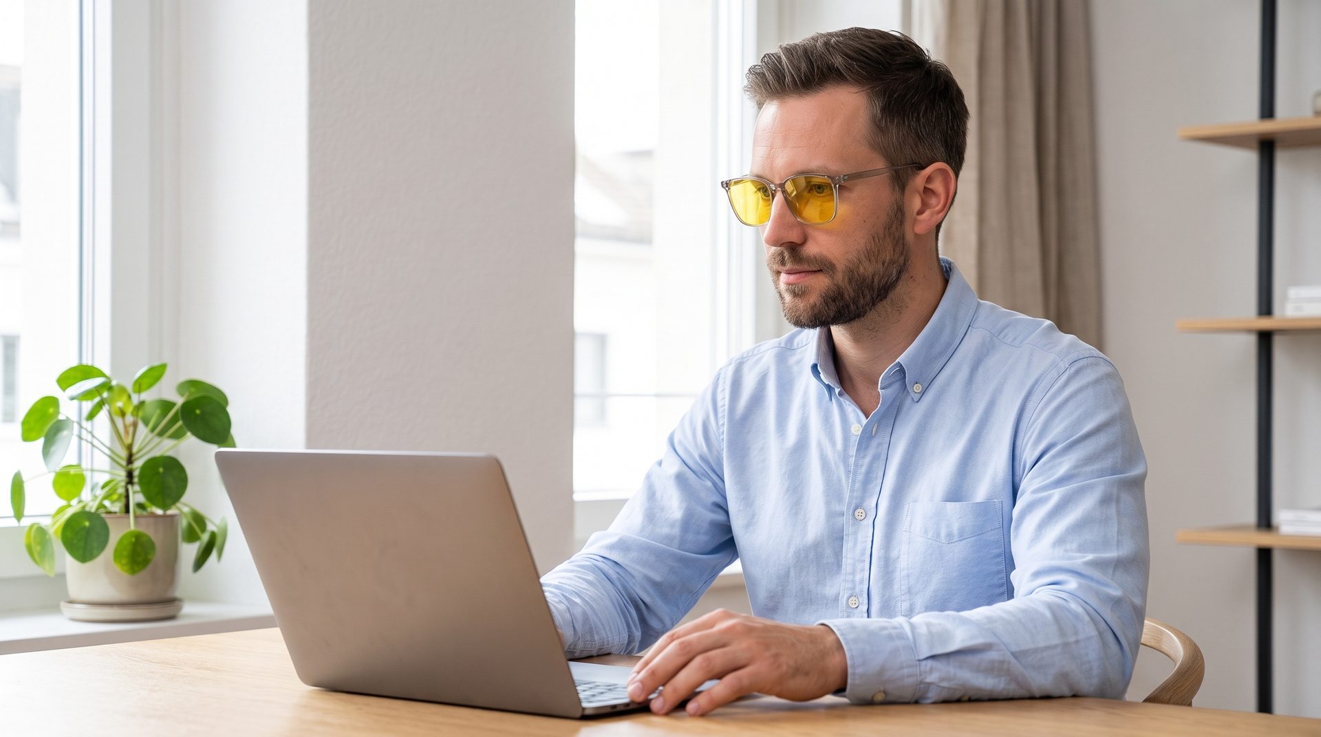 Man working on a laptop in a bright apartment, wearing VERONA 001 with Giallo lenses