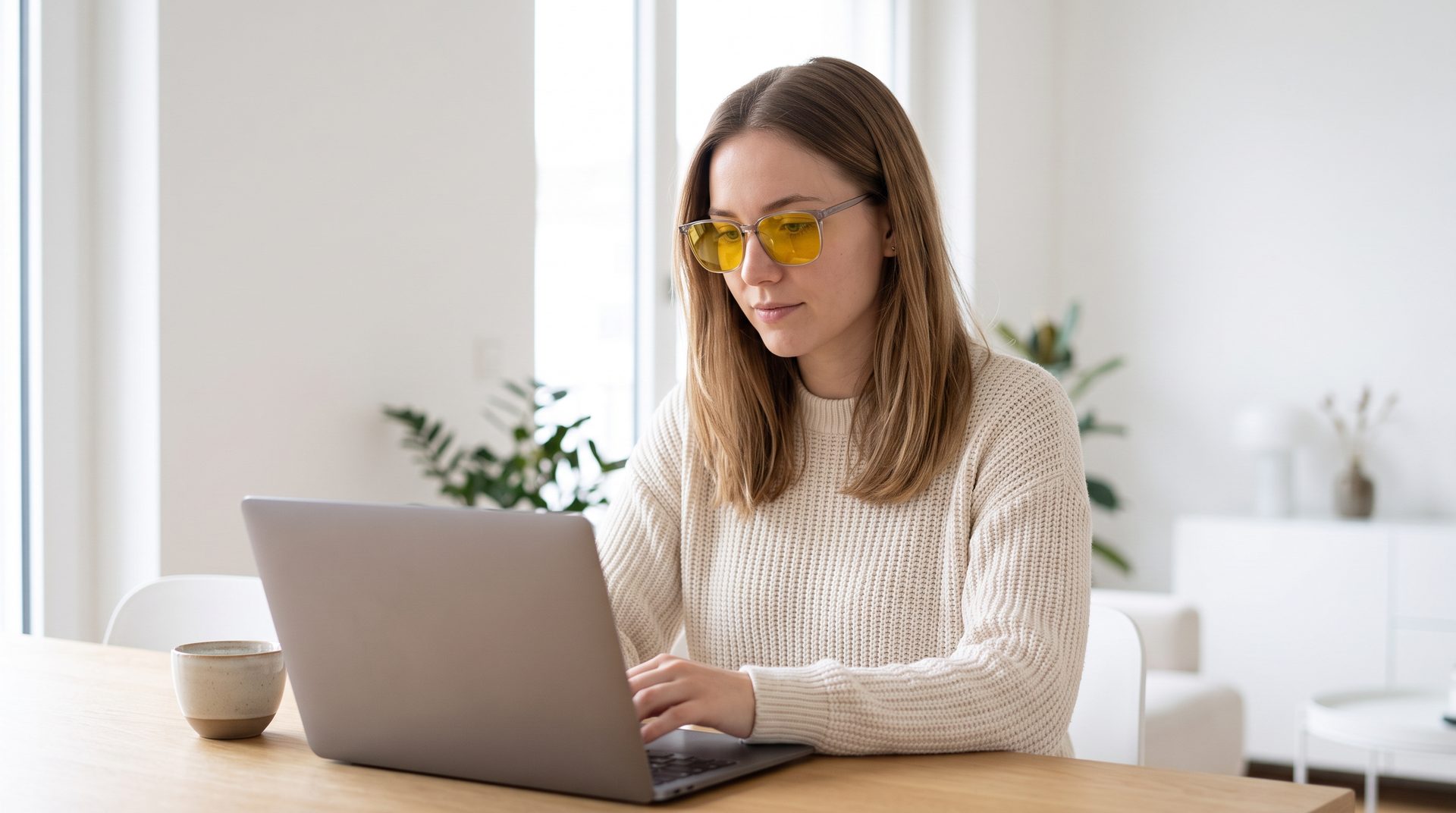 Woman working on a laptop in a bright apartment, wearing VERONA 001 with Giallo lenses